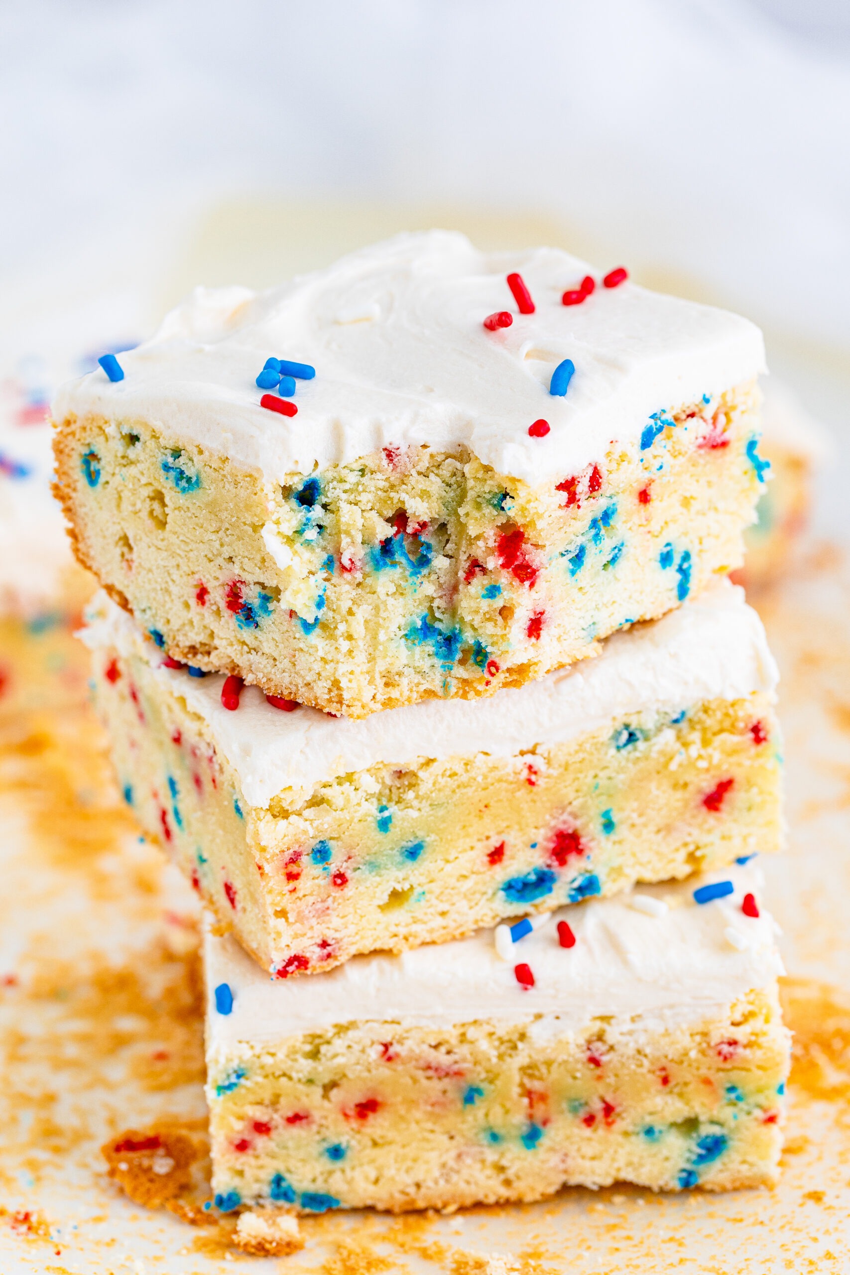 Front view of three Patriotic Sugar Cookie Bars stacked with a bite removed from the top bar.