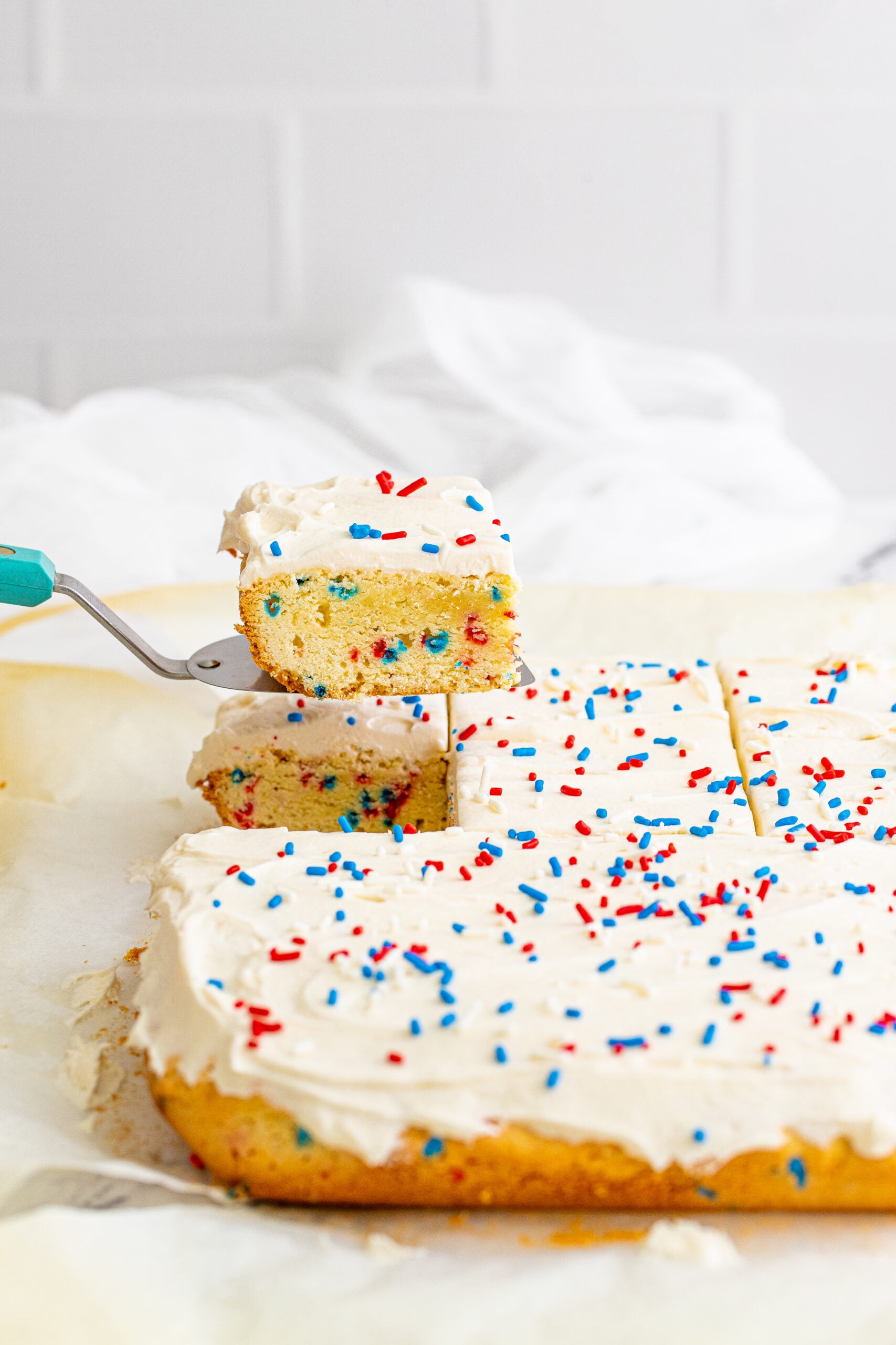 Front view of a cake server removing a piece of Patriotic Sugar Cookie Bars.