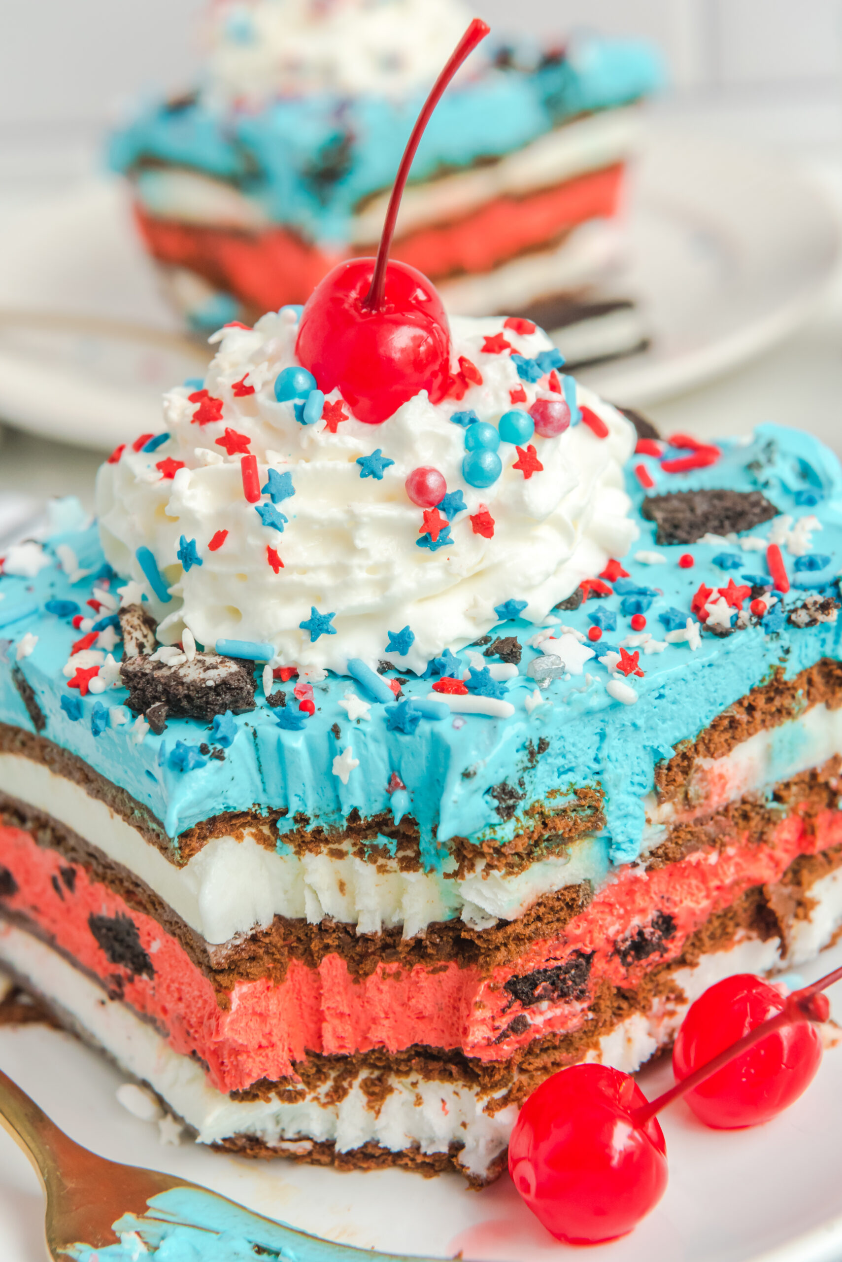 Overhead view of a slice of Patriotic Ice Cream Sandwich Cake topped with whipped cream and cherry.