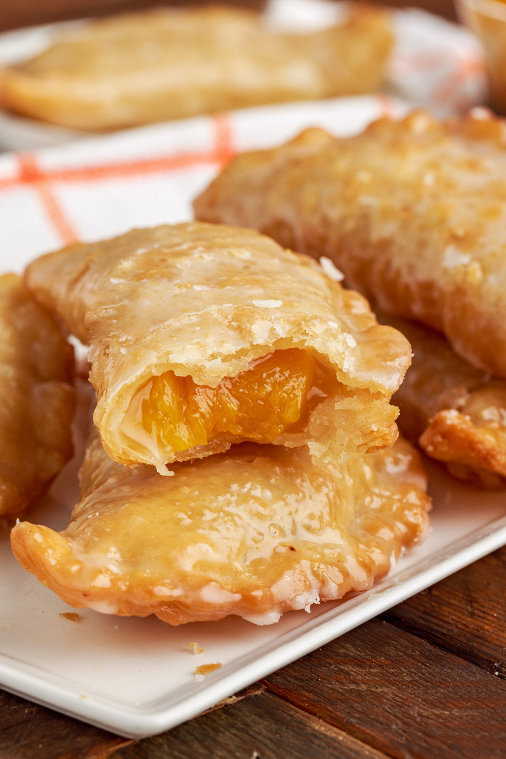 Up close view of Peach Hand Pies stacked with a bite removed from the top pie.