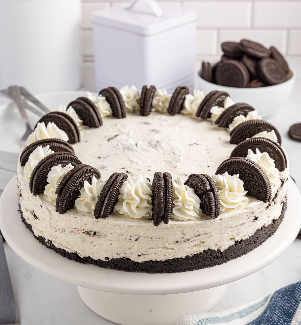 no bake oreo cheesecake on a white cake stand unsliced