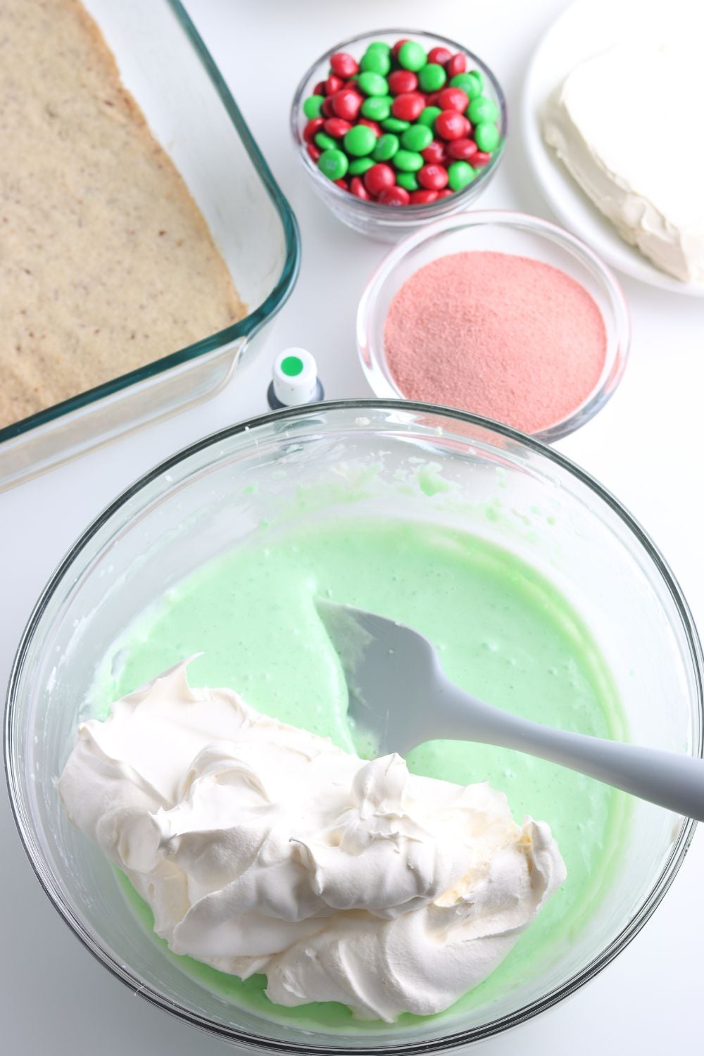 folding whipped cream into a green jello mixture
