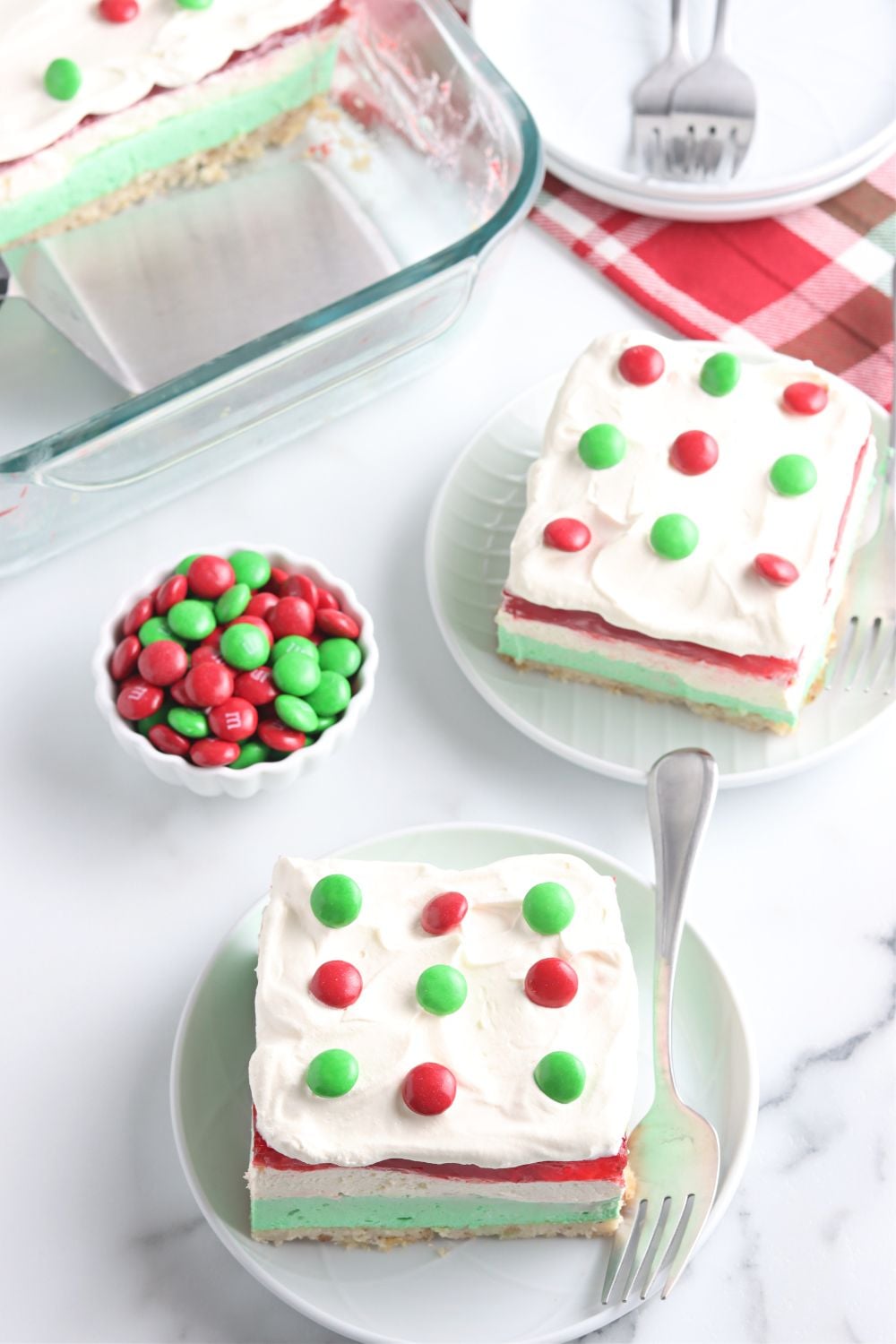 plates with a dessert lasagna for christmas on it and a bowl of festive M&Ms on the side