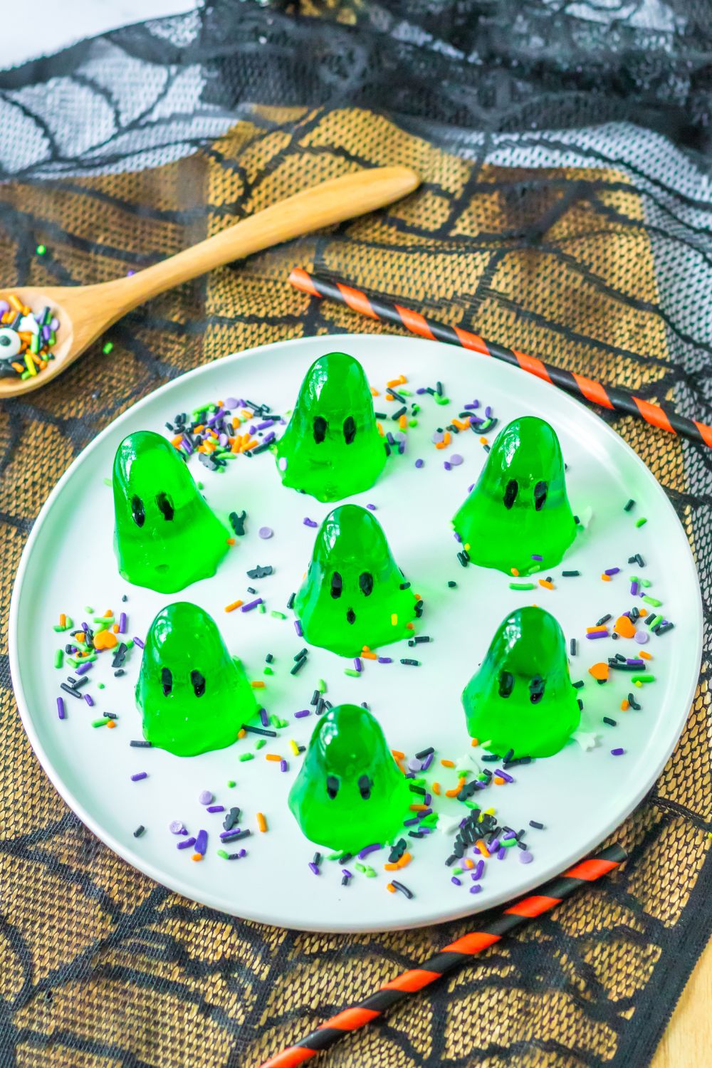 platter with green ghost jello shots on it with a spider web coaster under the platter