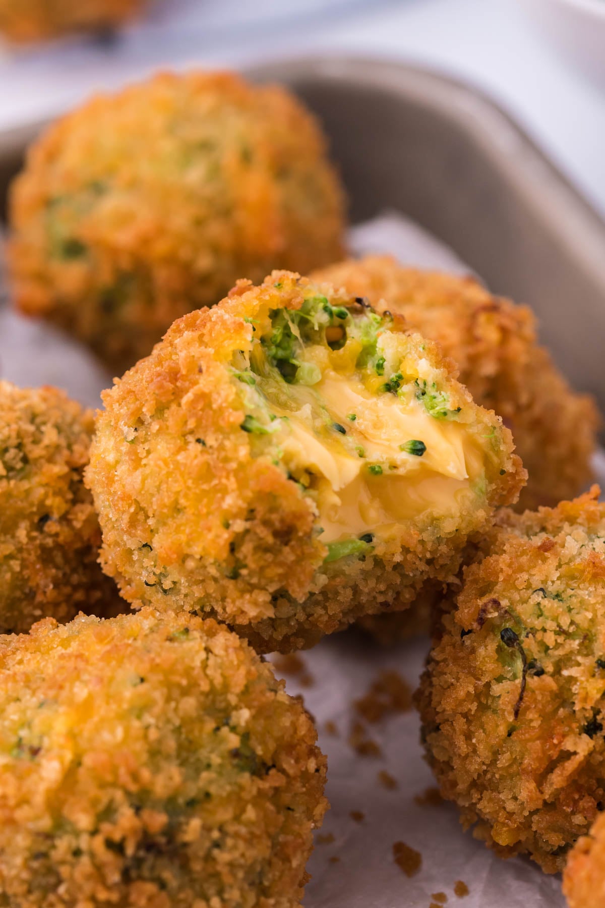 Broccoli Cheese Bites piled on eachother with a bite taken out of the top one