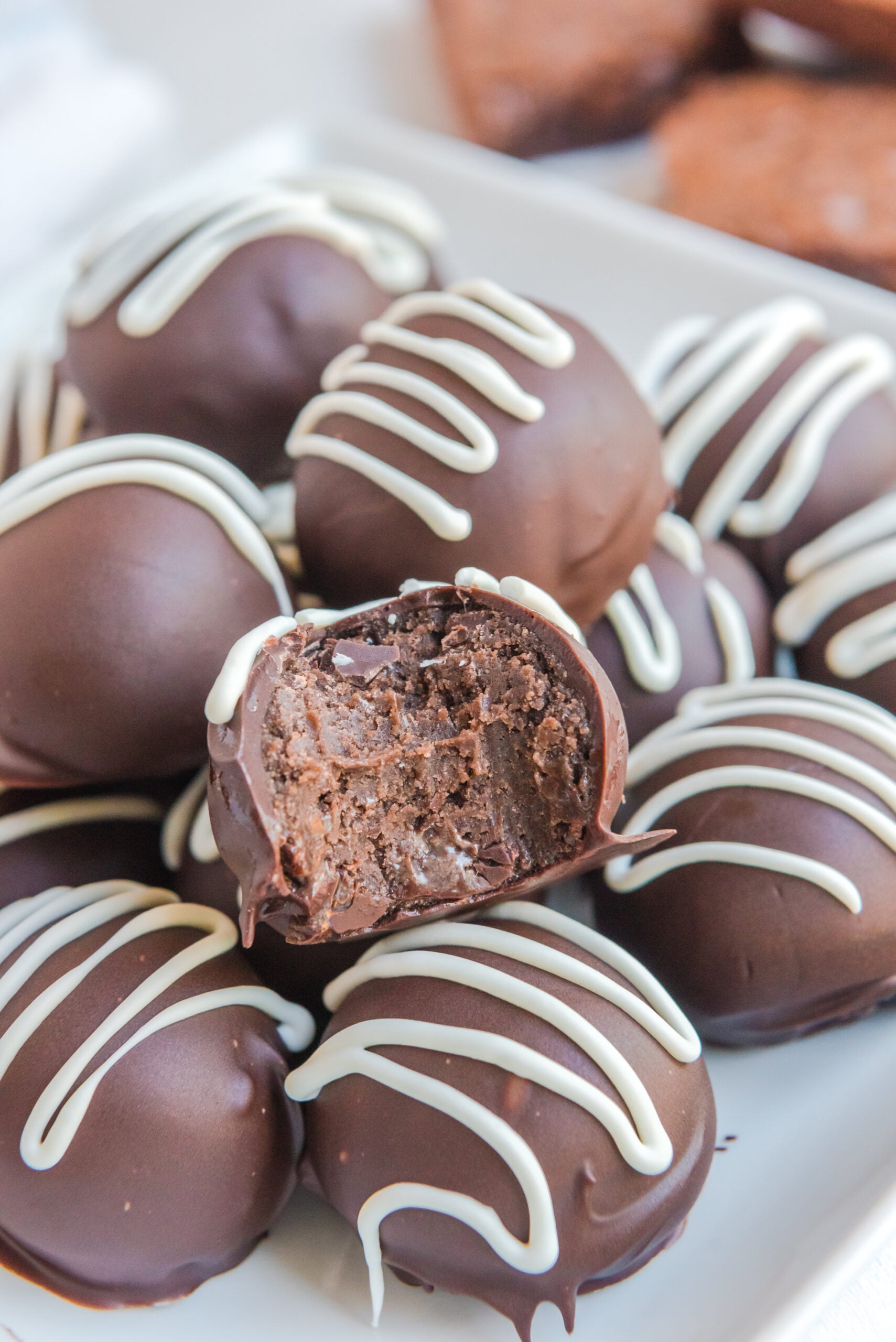 Up close photo of the Brownie Bite Truffles on a white plate with a bite taken out of the top one
