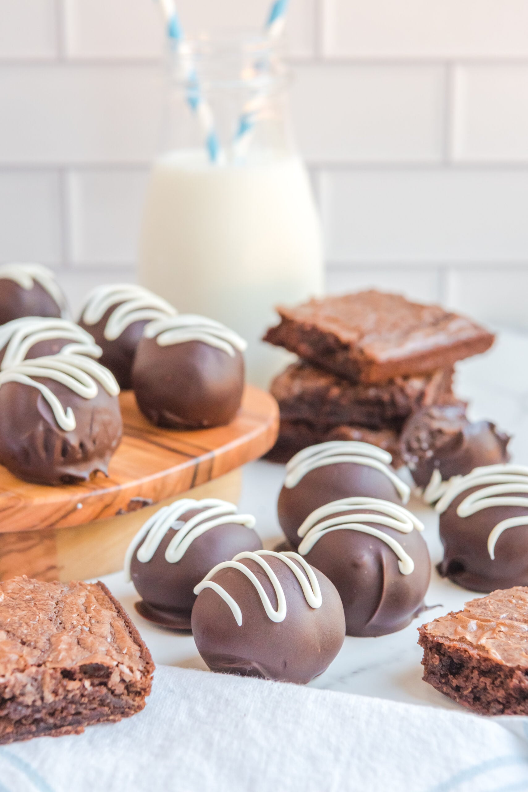 Brownie Bite Truffles on a white table with brownies stacked behind them and all around them