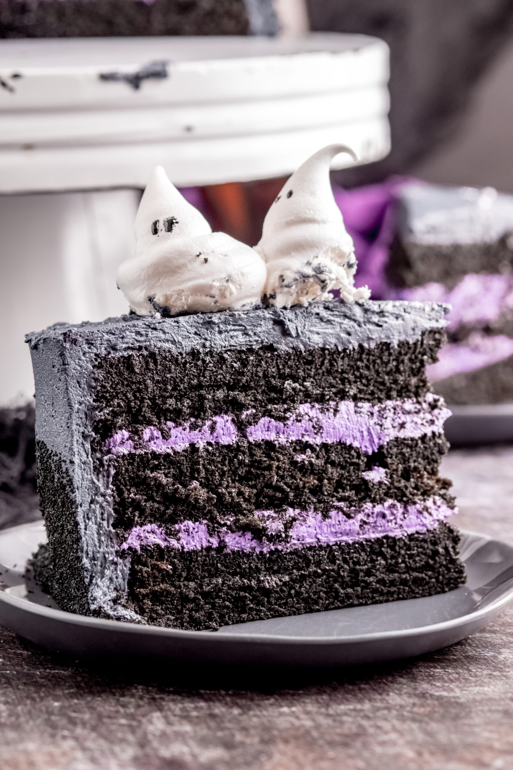 Side view of the Halloween cake slice on black plate showing the purple frosting layers