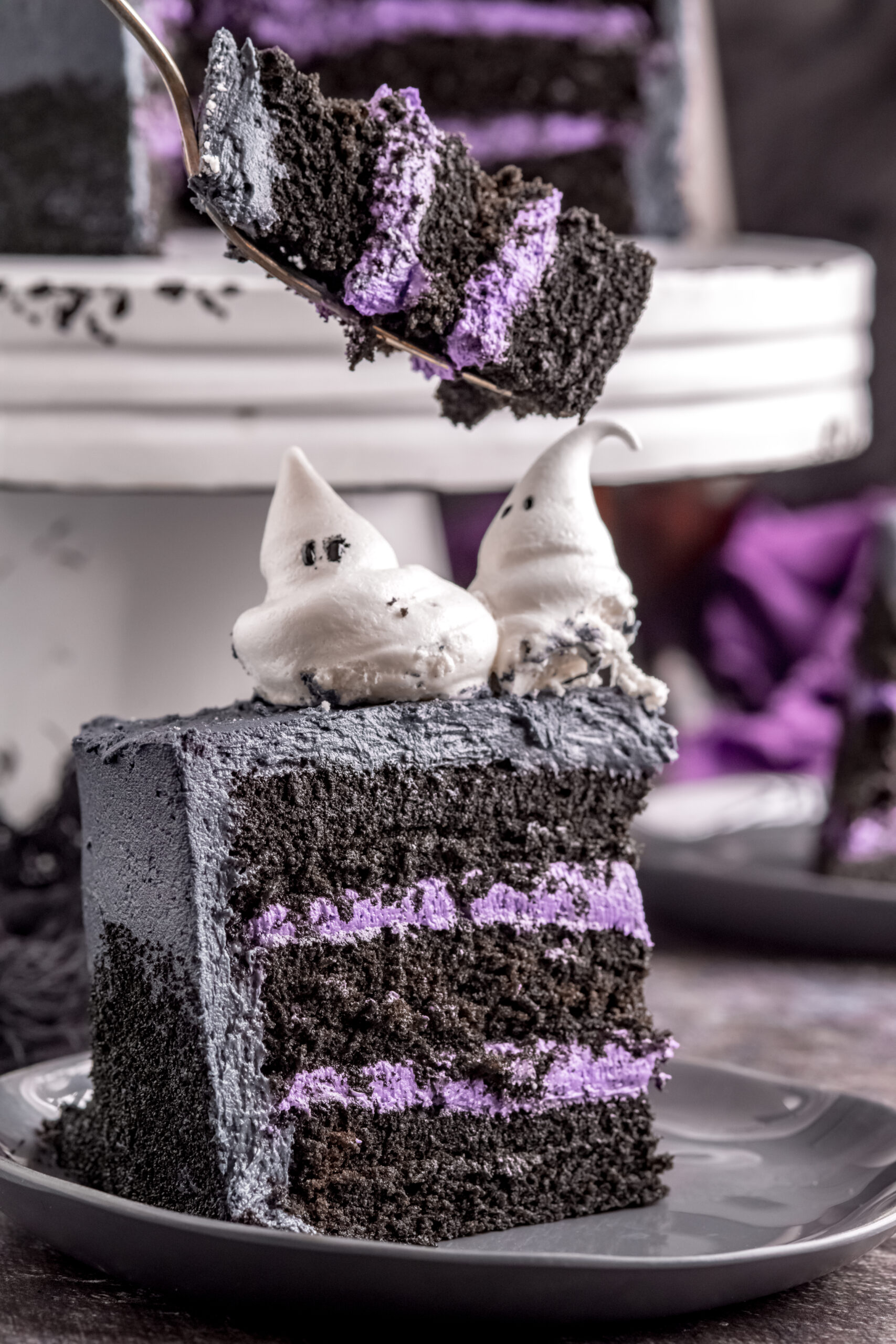 Halloween cake slice on black plate showing the purple frosting layers