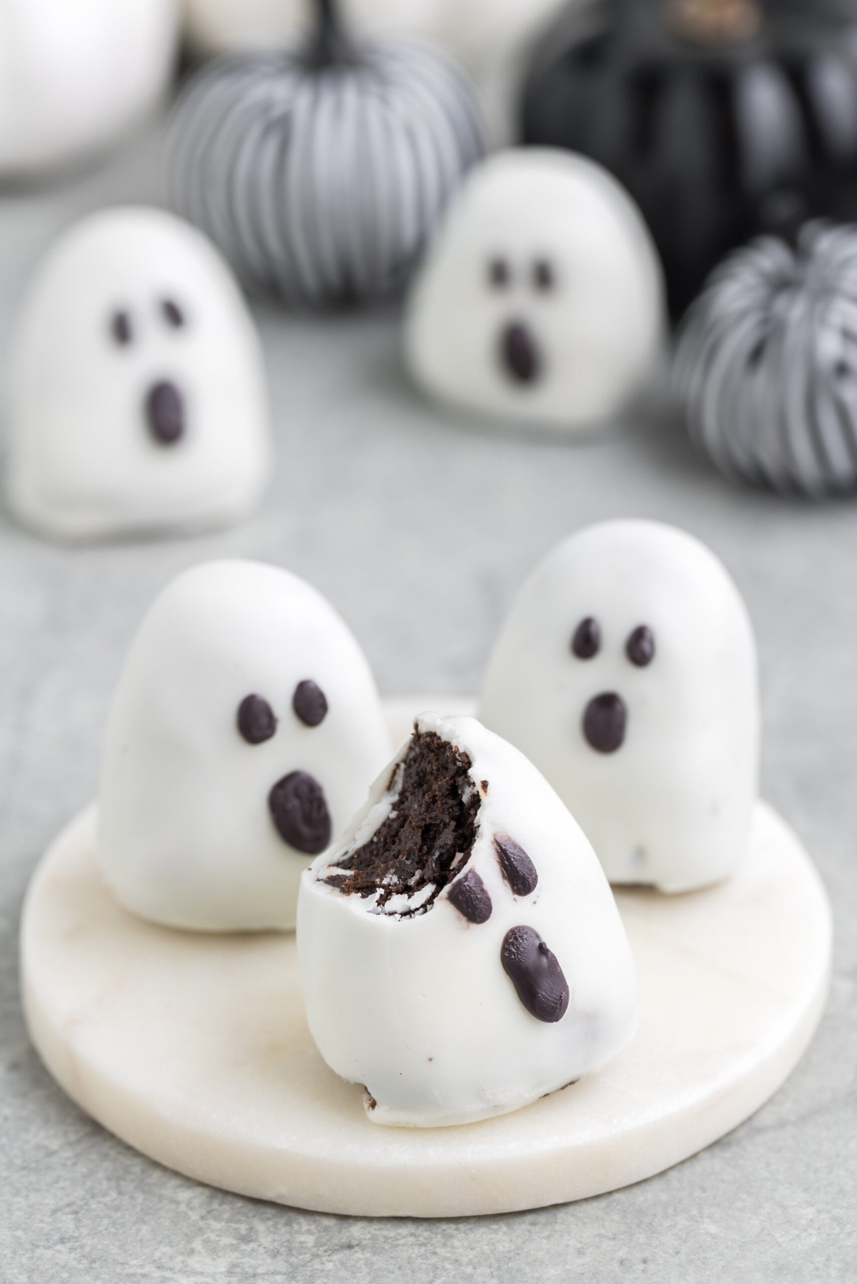 Oreo ghost truffle with bite taken out sitting on a platter on table