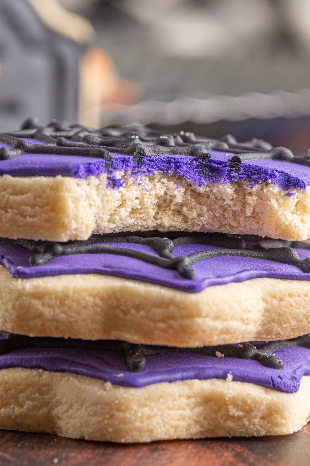 stacked sugar cookies on table with one that has a bite taken out of it