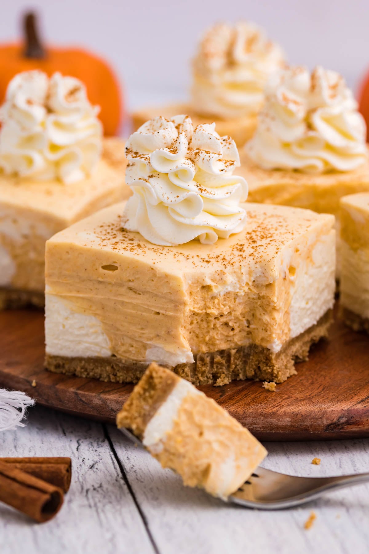 no bake pumpkin cheesecake bar with bite taken out sitting on a dark wood serving platter