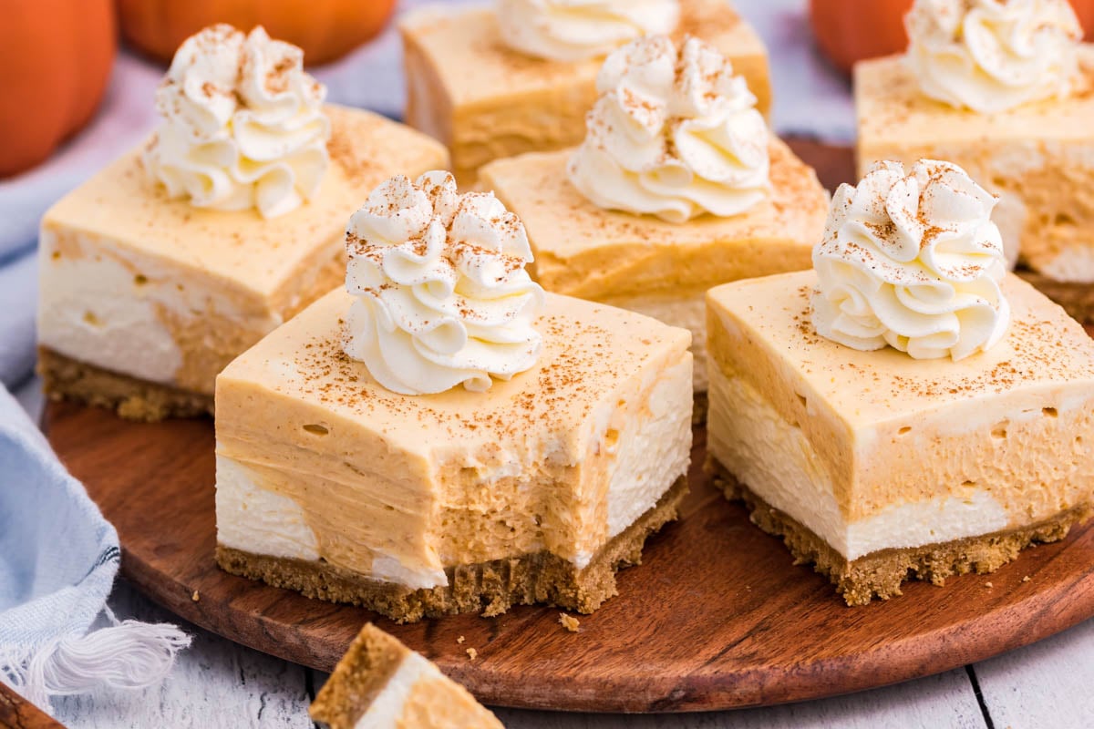 pumpkin cheesecake on a wood serving table with bite taken out of a slice
