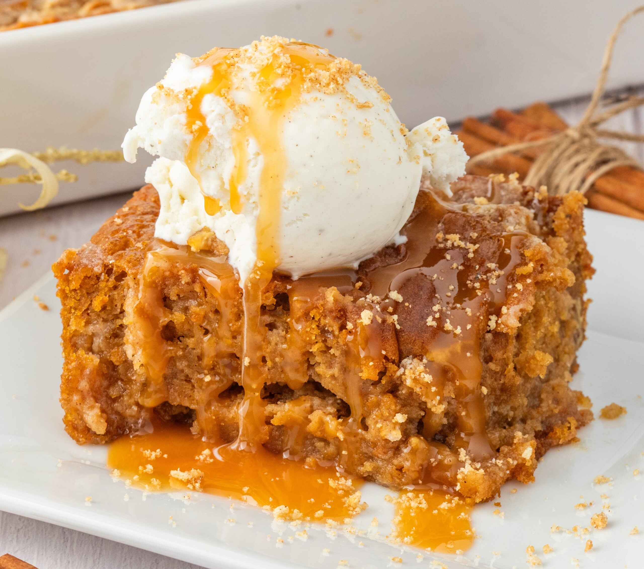 sliced earthquake cake on plate drizzled with caramel and a scoop of ice cream on top
