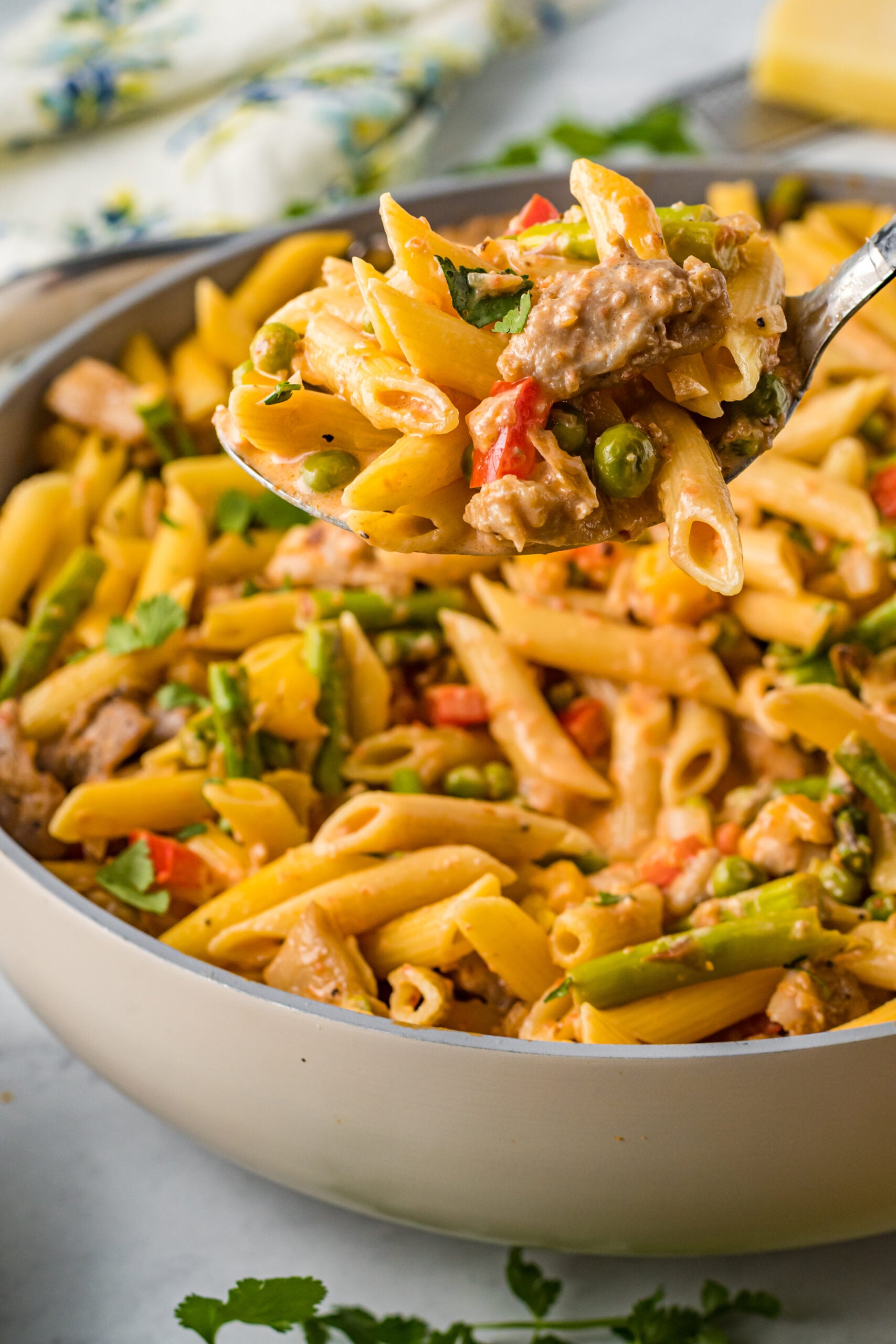 Side view of Cajun Chicken Pasta with a large spoon scooping out a bite