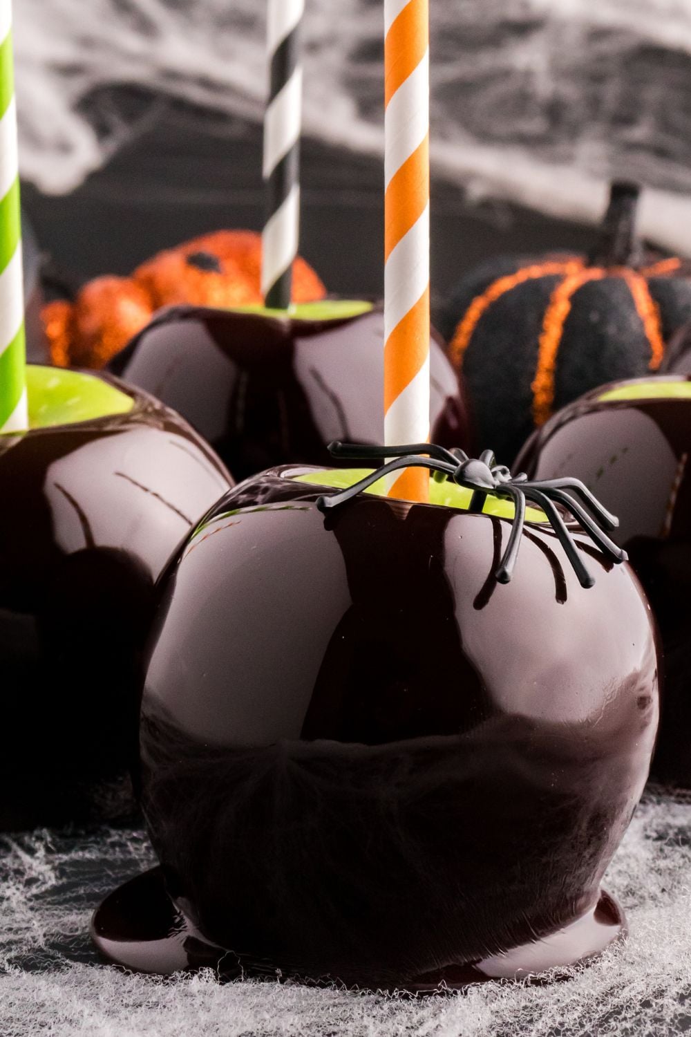candy apples on table with a candy apple with black spider on it for spooky looks