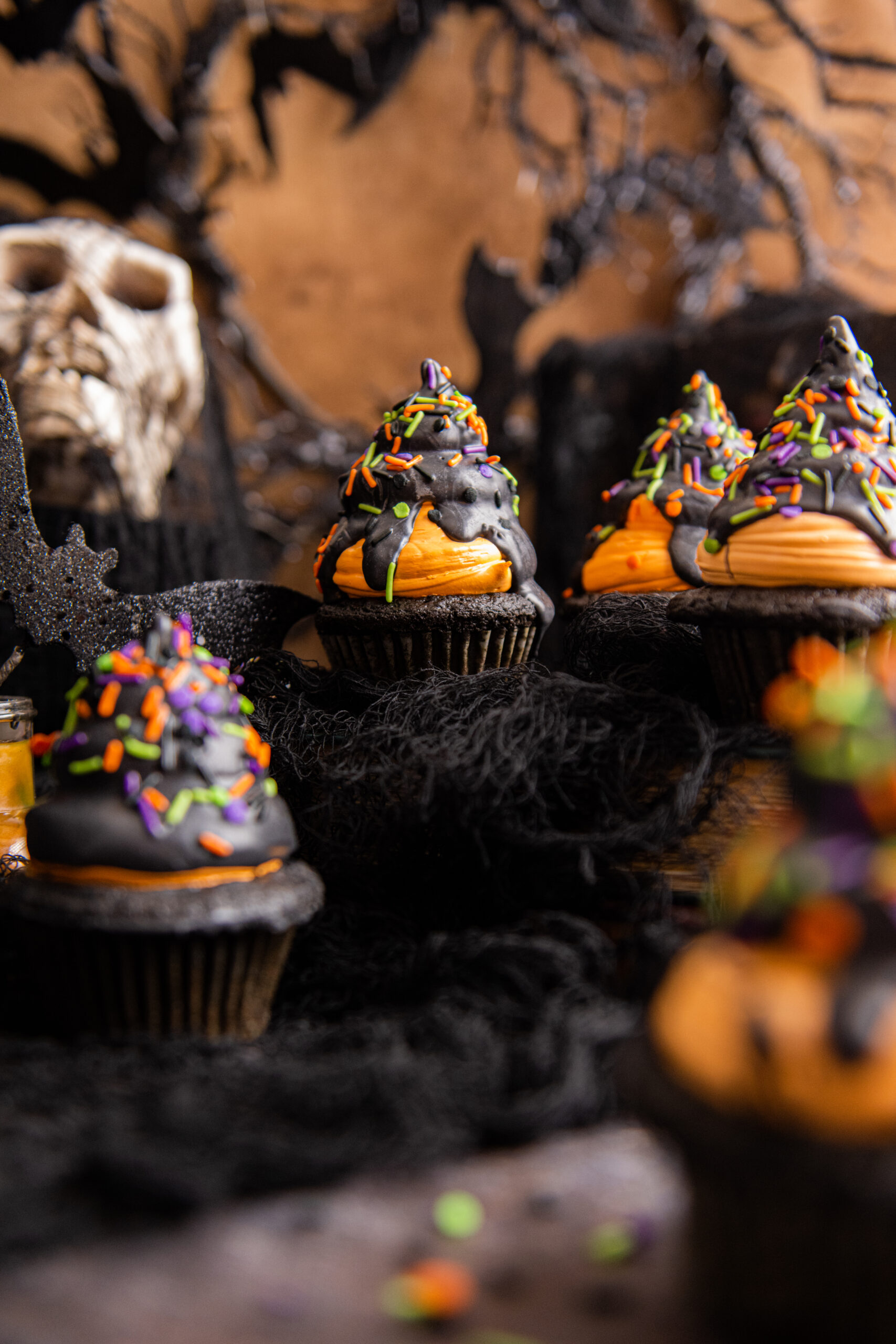 Halloween Cupcakes on a black table with halloween decor around it
