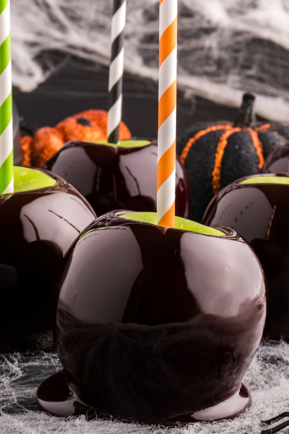 black caramel apples on counter with spider webs around it