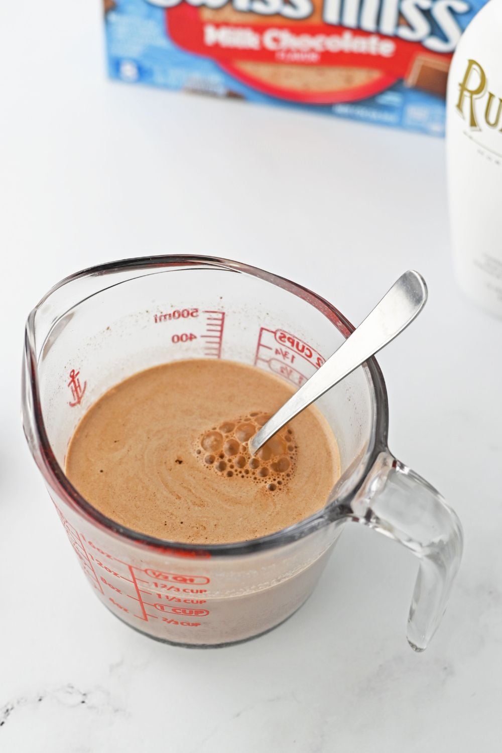 mixing hot chocolate in a measuring cup on table