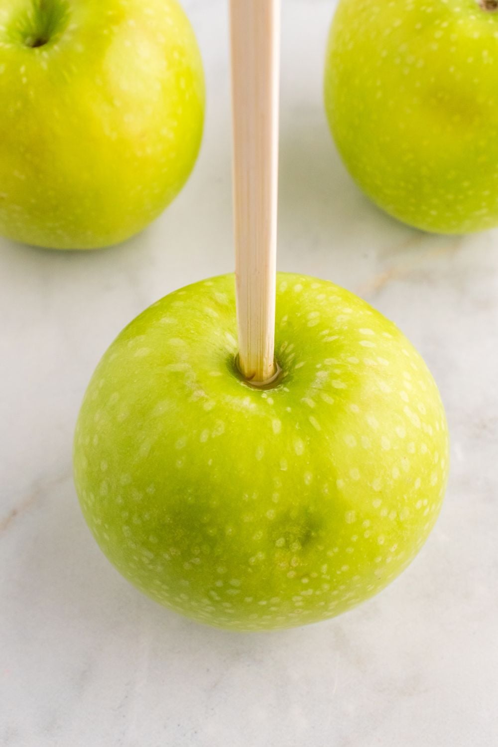 Granny Smith apples with a wooden skewer poked in top