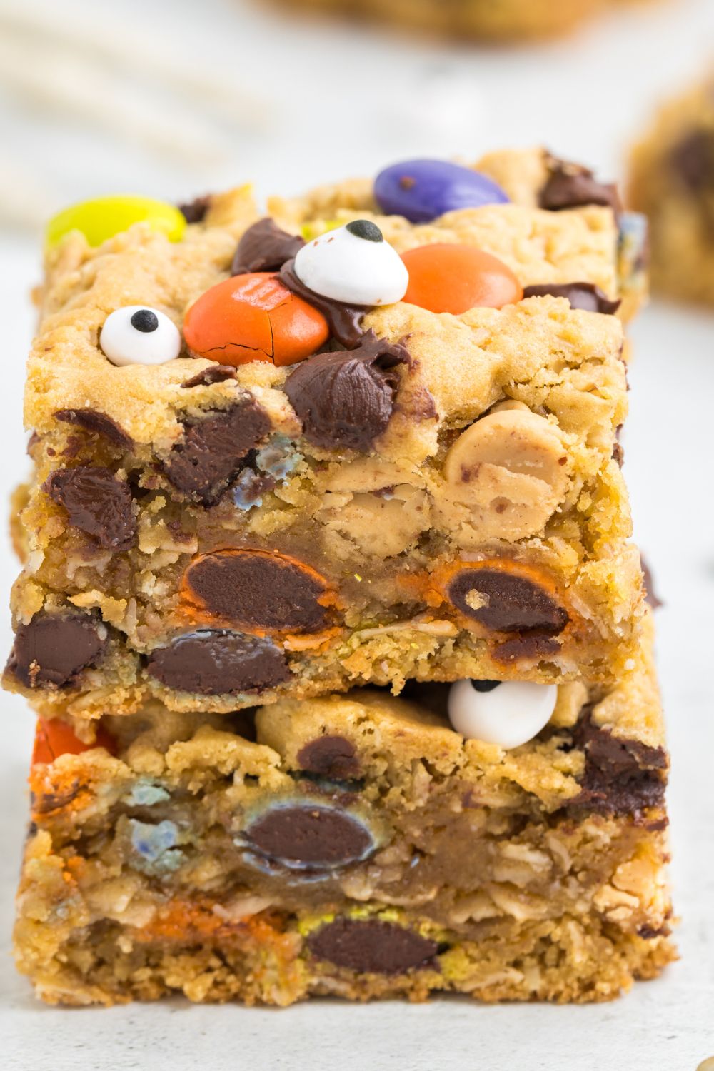 chewy bars stacked on top of each other on tale with cookie bars around it