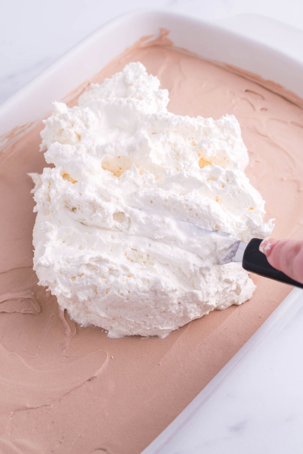 spreading whipped cream on top of french silk topping on brownies 