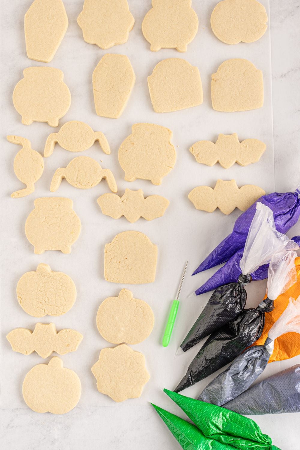 sugar cookies on counter with piping bags of frosting around it 