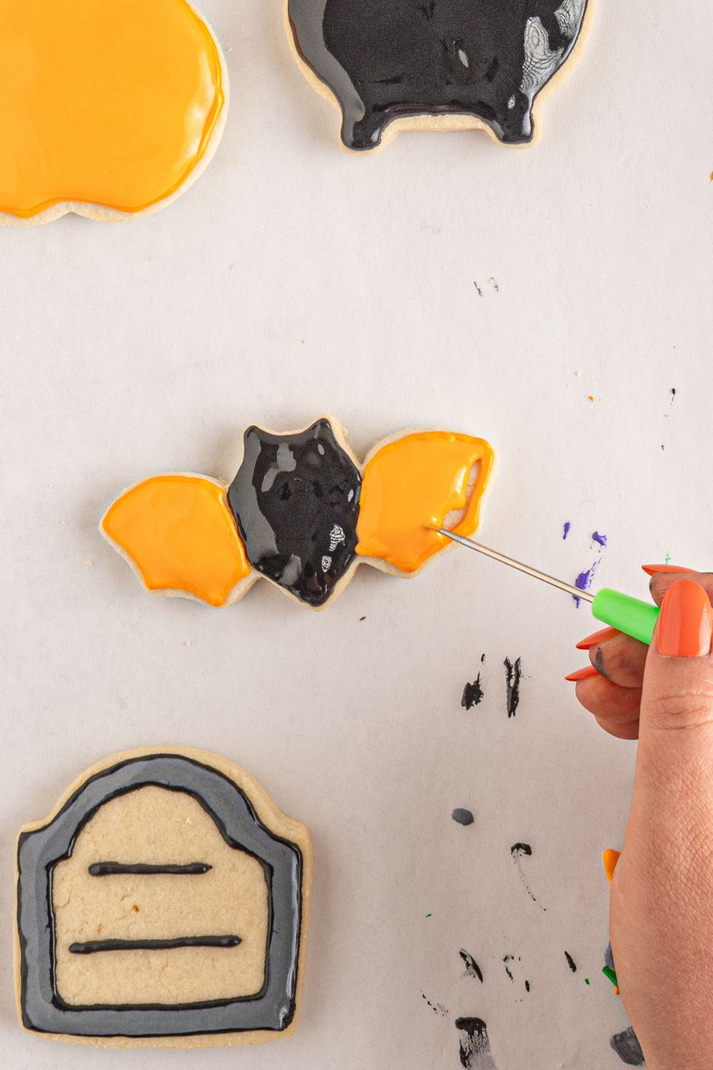 spreading the royal icing out on bat cookie 