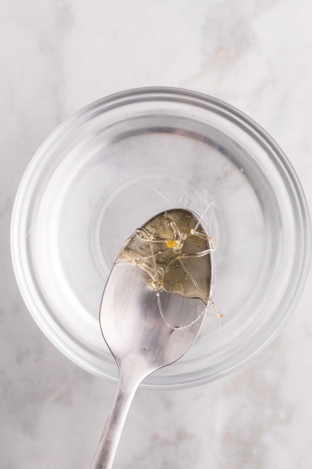 spoon with hardened candy coating on it above a bowl of water