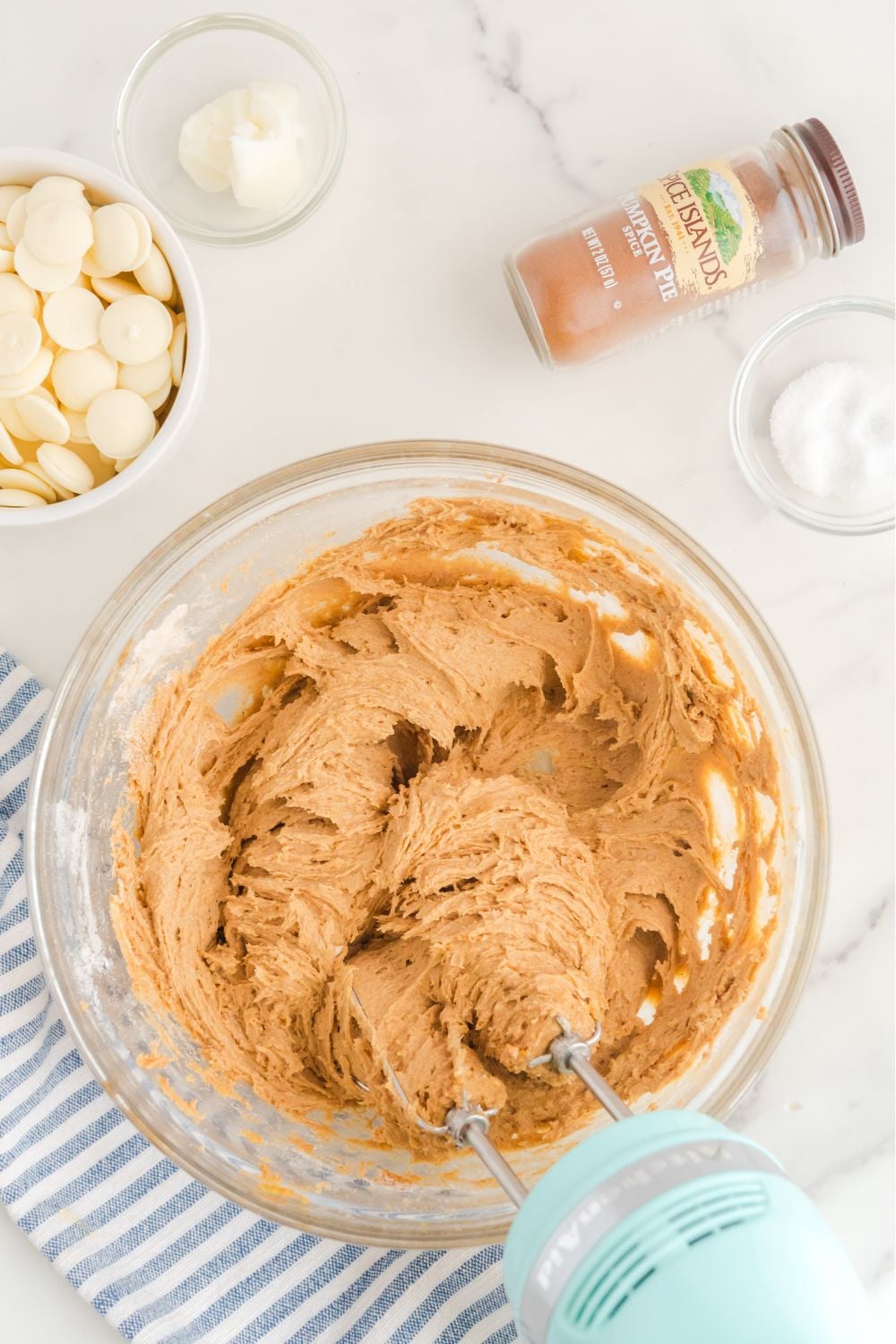 cheesecake pumpkin mixture being mixed with a hand mixer in a glass bowl 