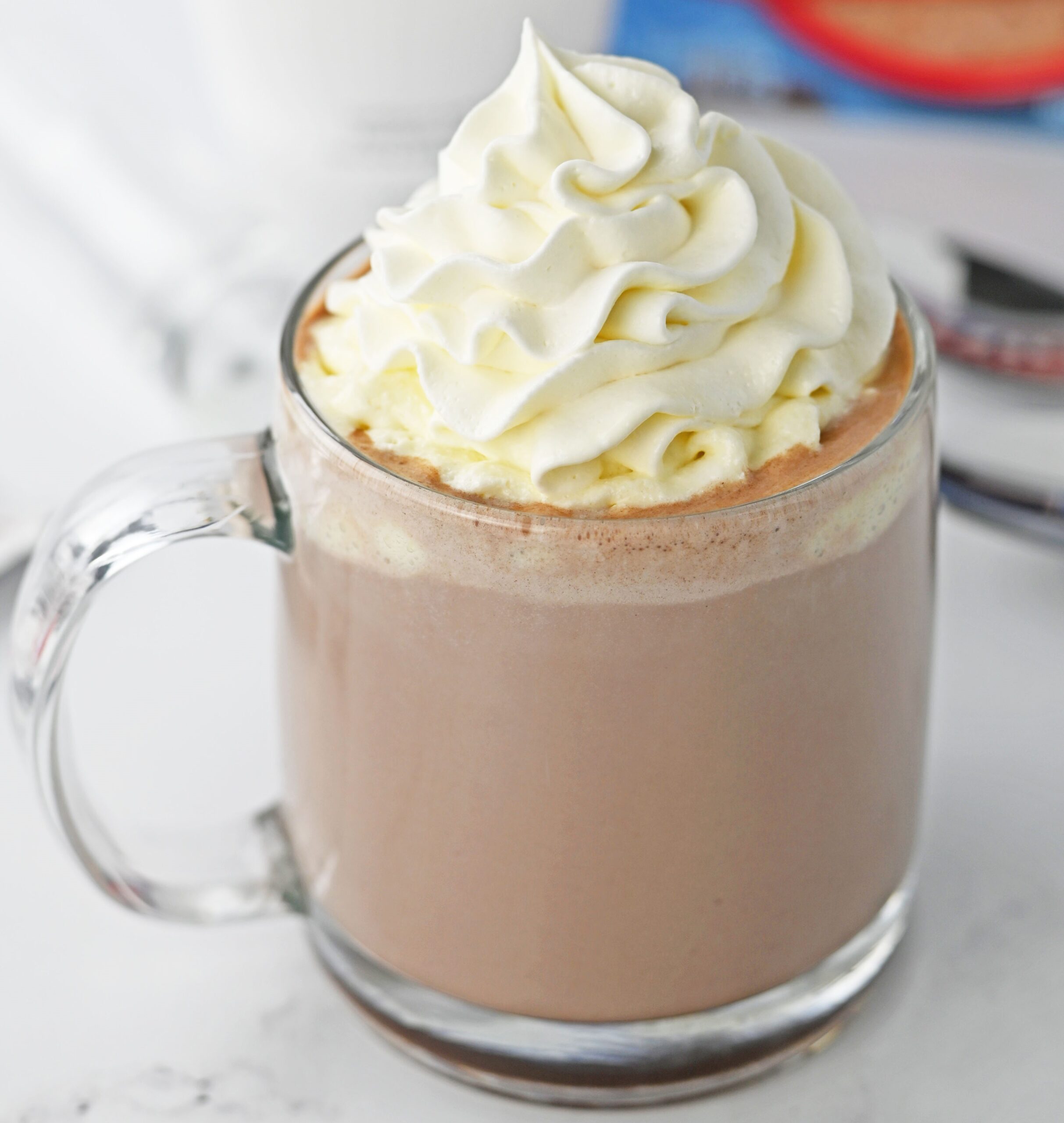 up close shot of a hot chocolate rumchata in a clear glass mug topped with whipped cream