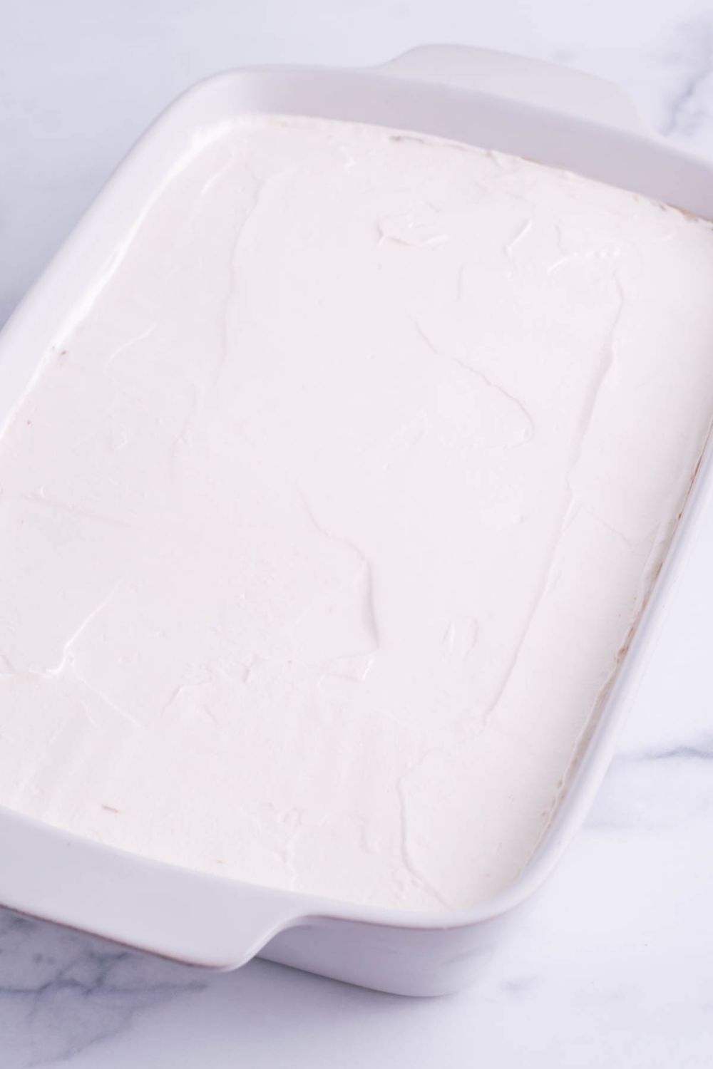 smoothed whipped cream in a 9x13 baking dish on table 