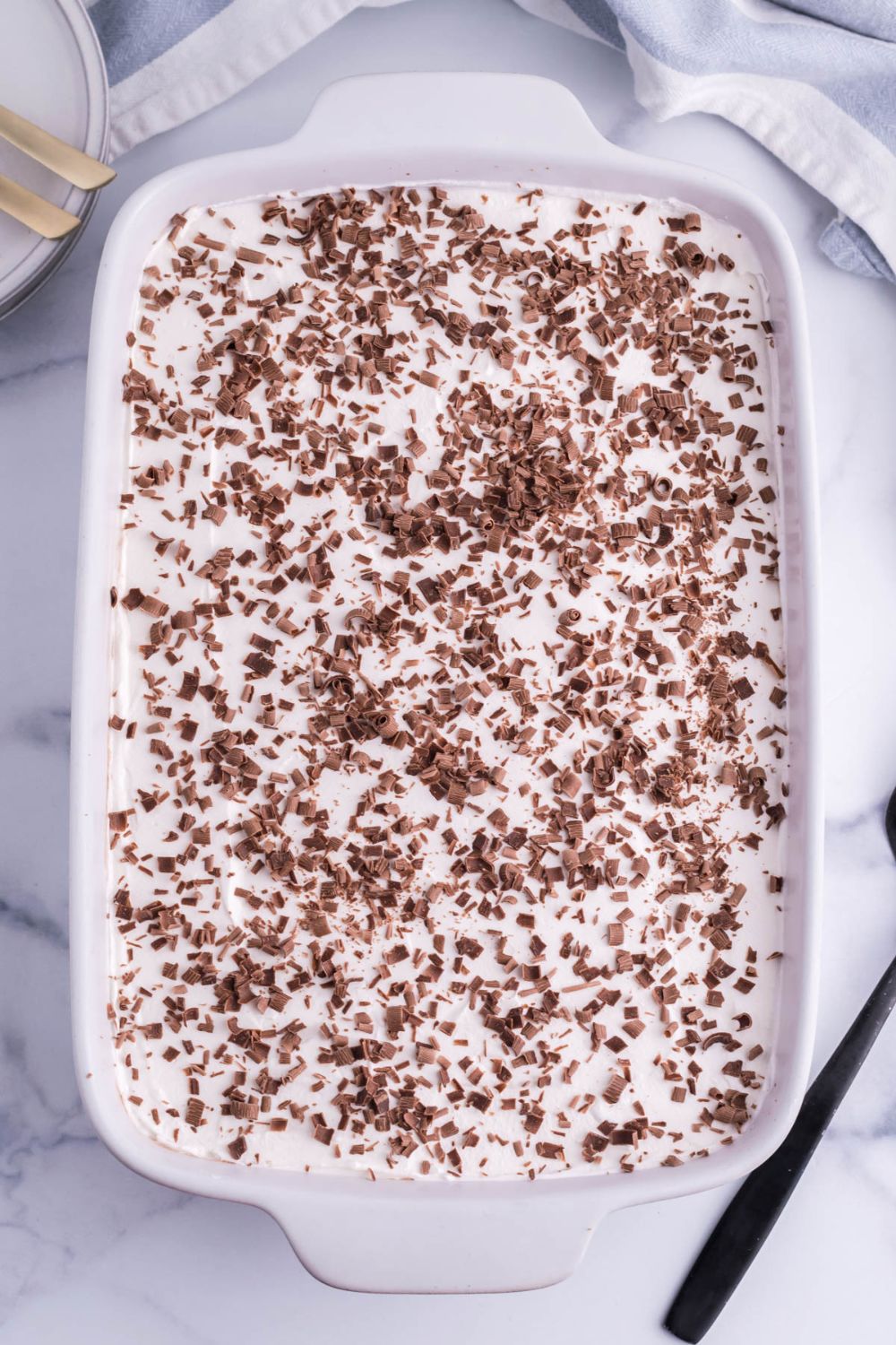 chocolate shavings topped on french silk pie brownies in a 9x13 baking dish on a marble table