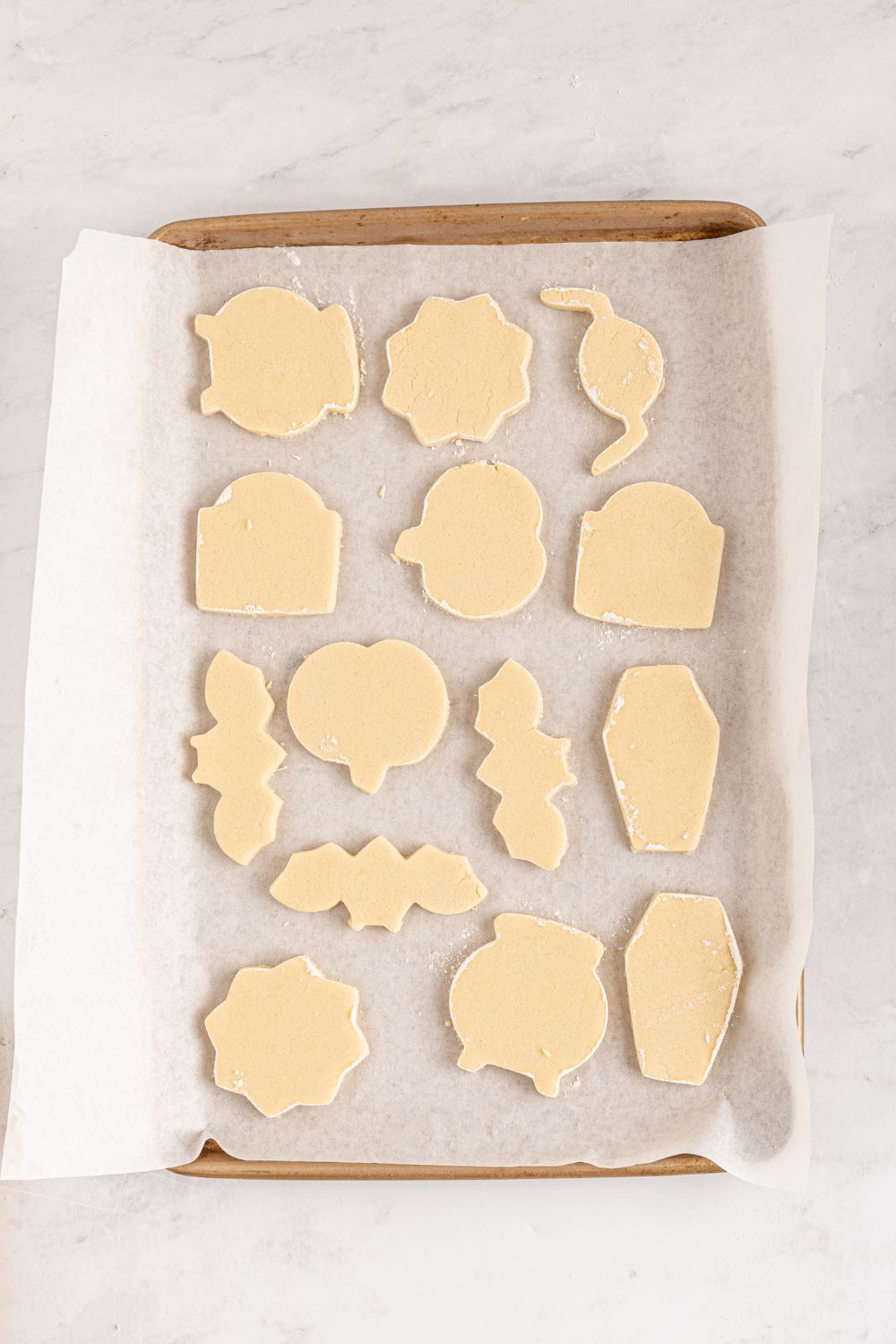 Halloween shaped sugar cookies on a baking sheet in raw shapes 