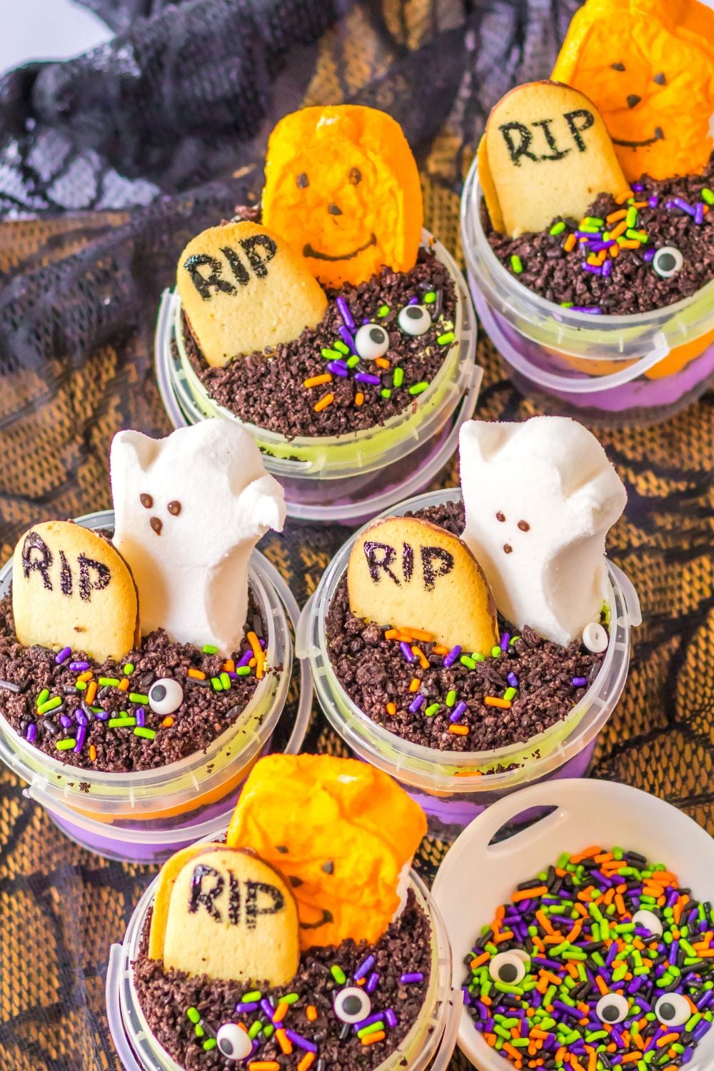 halloween pudding cups in containers on table with a bowl of sprinkles beside it