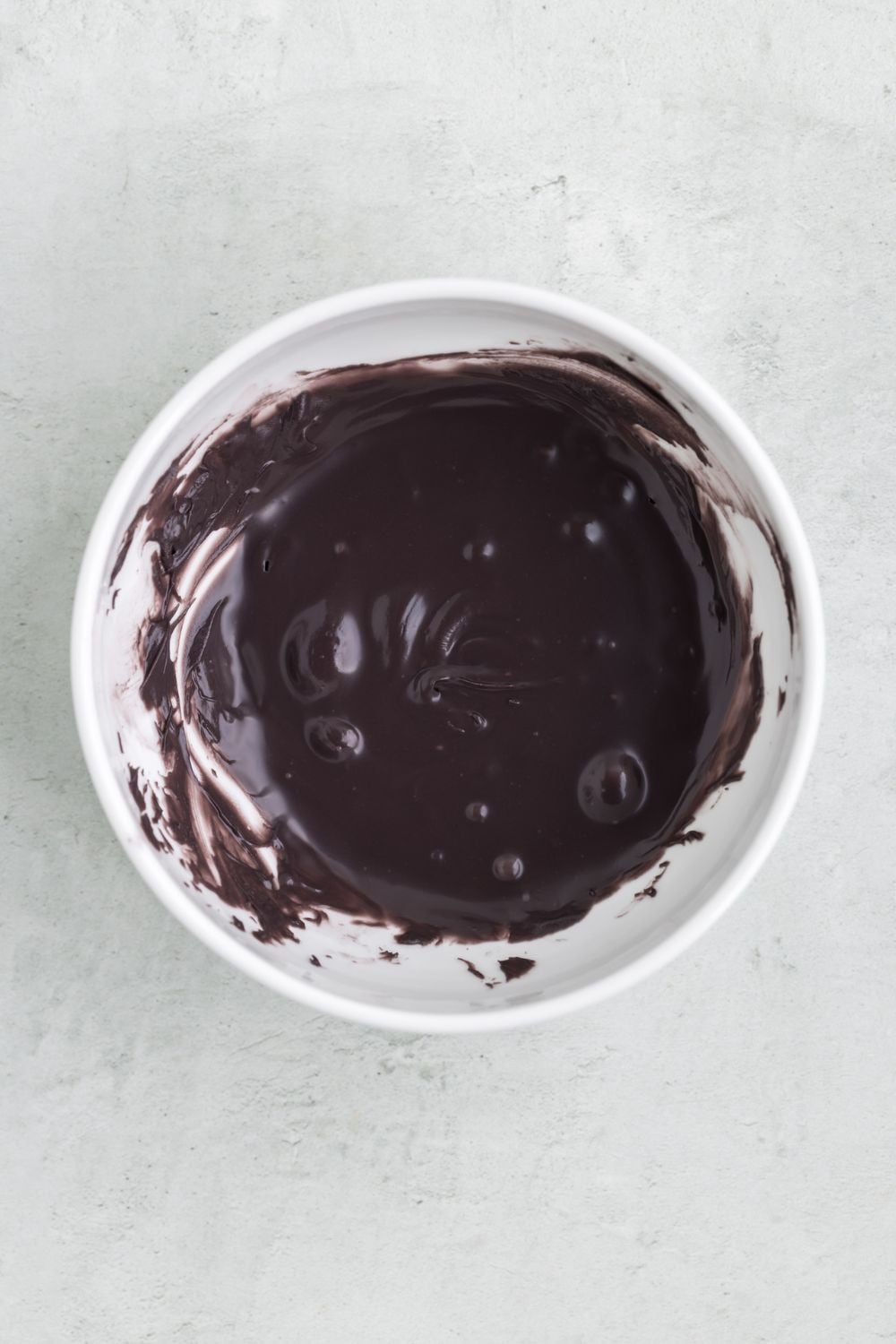melted black candy melts in a white bowl on table