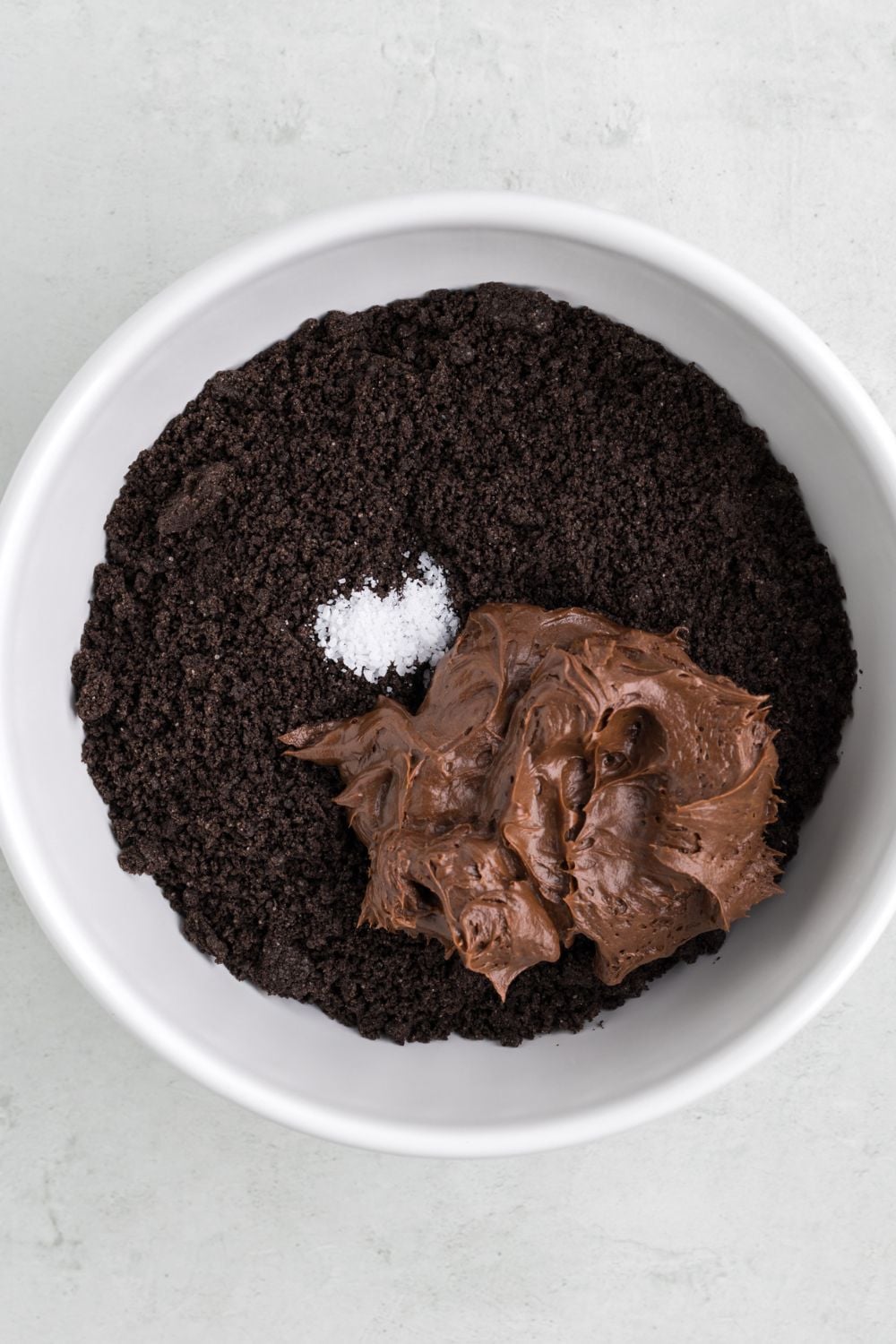 crushed oreos in a bowl topped with chocolate frosting and a little salt