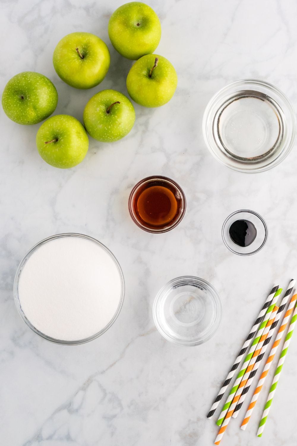 ingredients to make black candy apples sitting on marble counter top