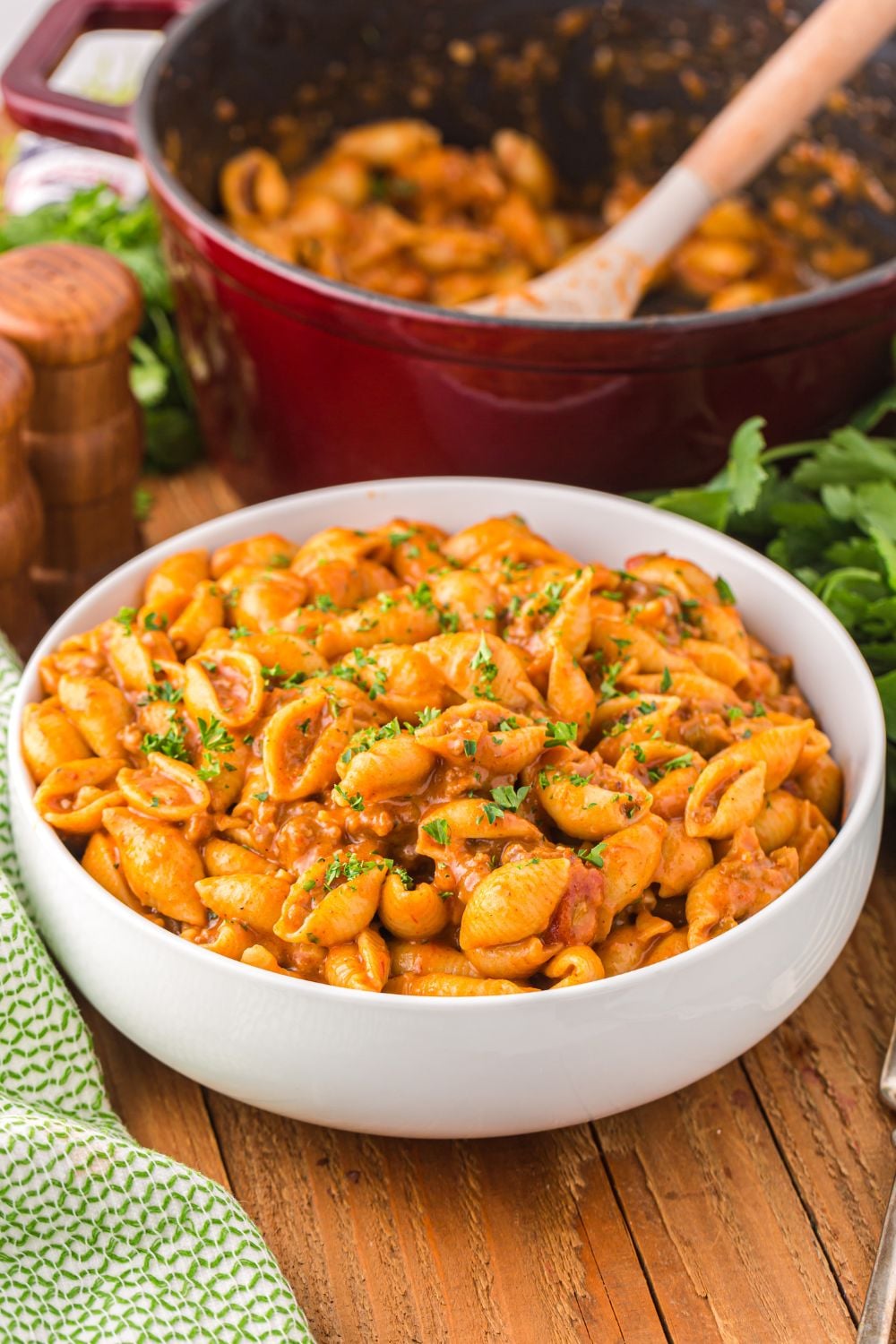 bowl of taco pasta on table with skillet of pasta behind it