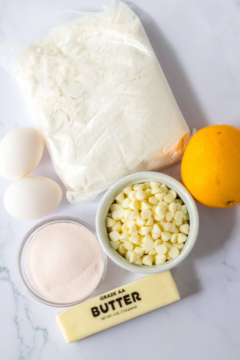 ingredients for orange cookies sitting on a marble table 
