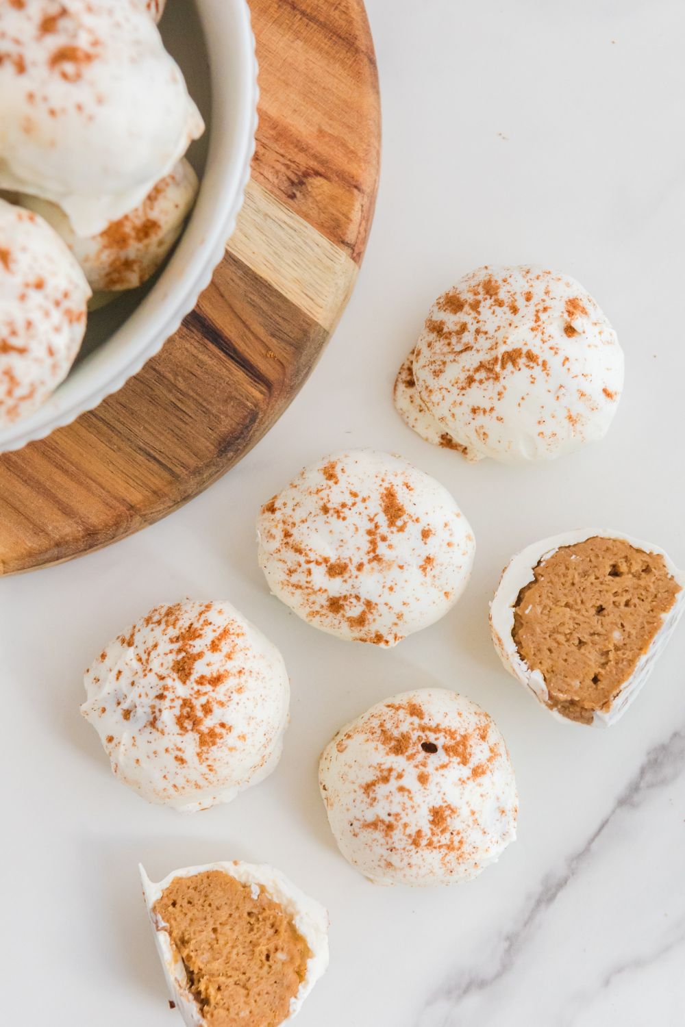 no bake pumpkin cheesecake bites on table some are cut in half to show filling