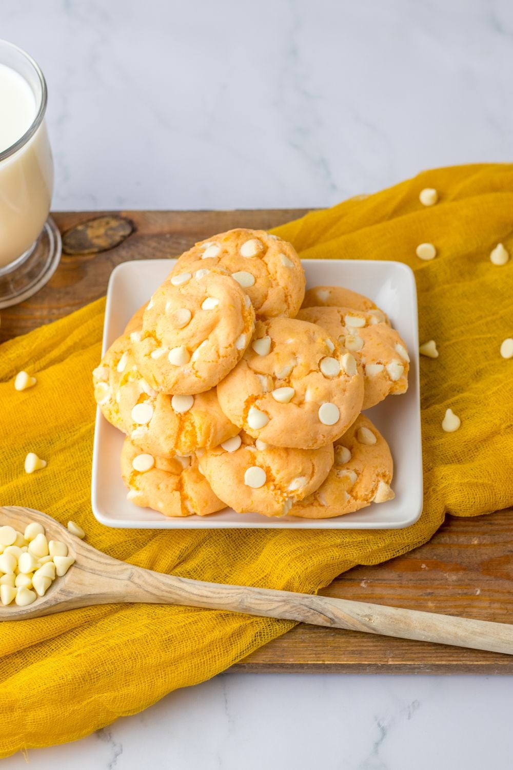 overhead view of orange cookies on tray with a wooden spoon with chocolate chips in it