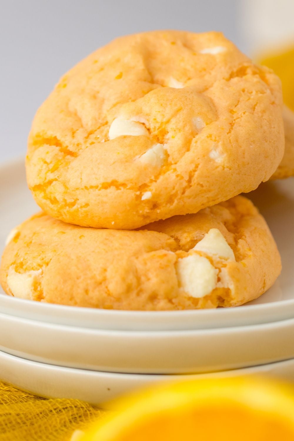 orange creamsicle cookies stacked on a set of plates with an orange sitting in the front