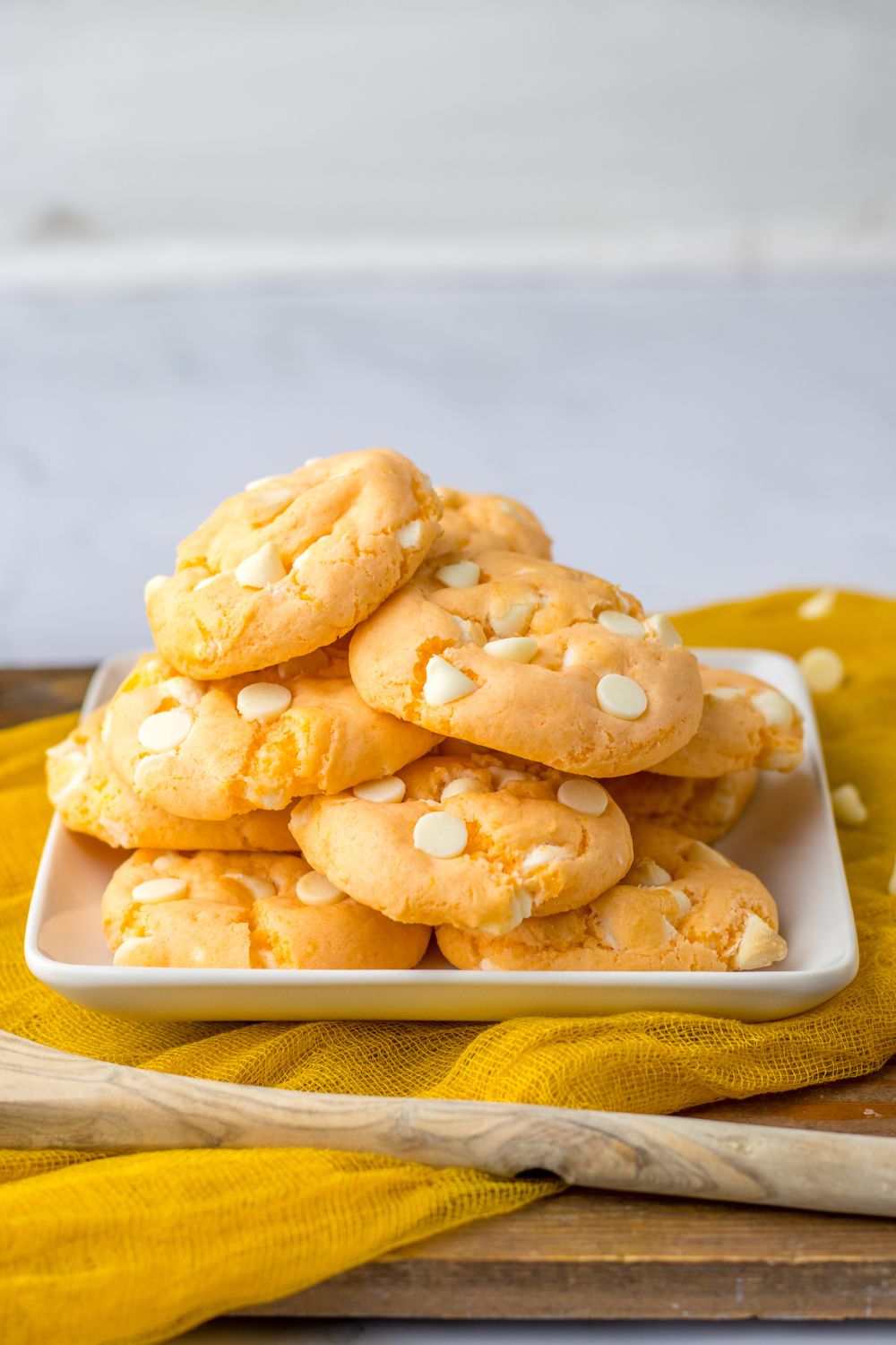 orange cream cookies stacked on a plate with orange towel under it