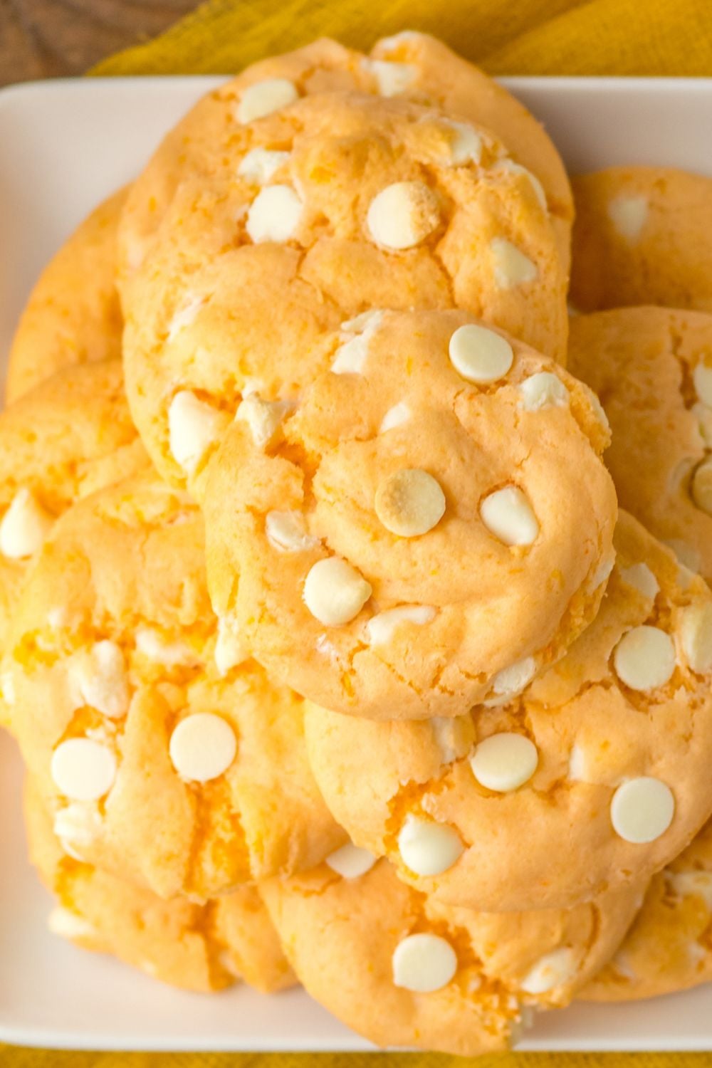 orange creamsicle cookies stacked on a white plate sitting on table