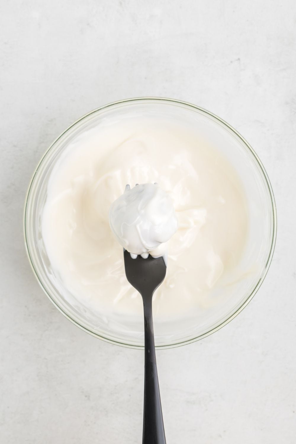 oreo ball dipped in white chocolate being held with a fork ablve the bowl
