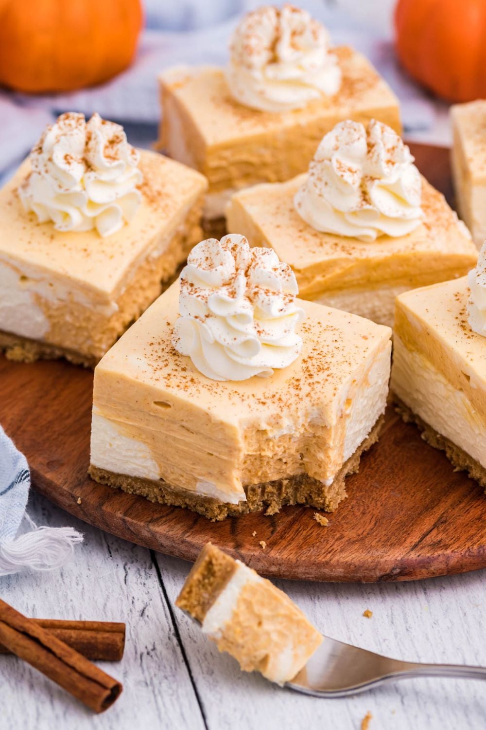 cheesecake bars on table with a fork and a bite on one sitting in front