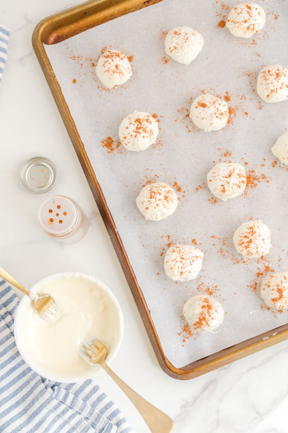 Pumpkin Spice Cheesecake Bites  on a baking sheet with melted choclate in a bowl beside it 