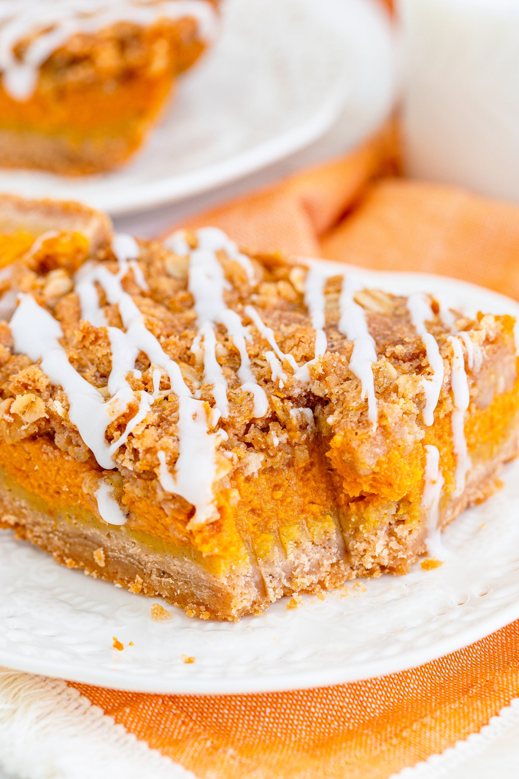 Pumpkin Streusel Bars on a white plate drizzled with glaze