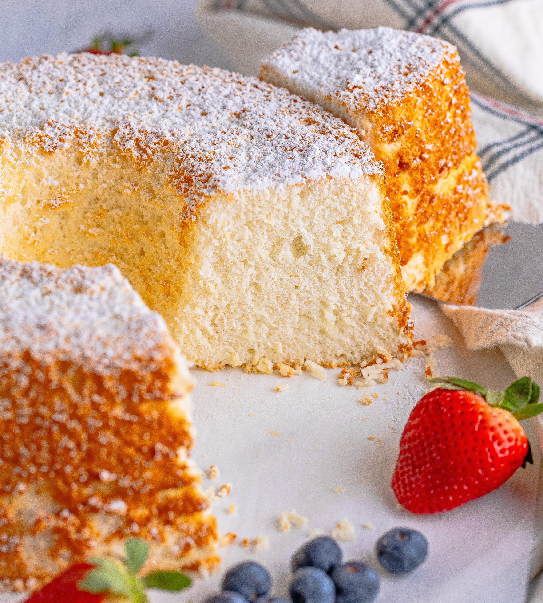 Angel Food Cake on a white serving platter with a slice removed 
